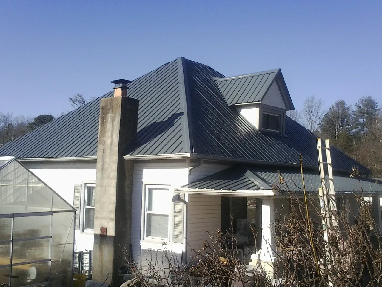 Dark blue standing seam metal roof on a white farmhouse with dormer — Slate & Tile Roof Repair by Roofing Brothers in Daisytown