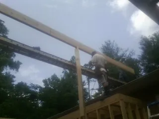Carpenter setting a ridge beam over a new addition frame — Ice Dam Removal by Roofing Brothers in Daisytown