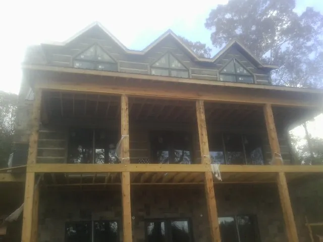 Dormers and porch framing on a large log home under construction — Roof Coating work by our crew in Daisytown