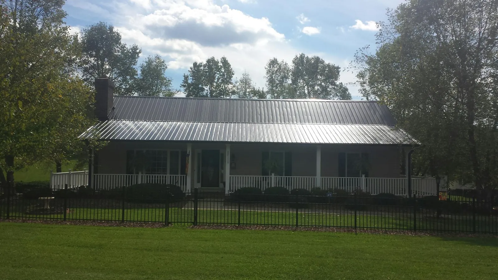 Gray metal roof on a brick ranch with a full width front porch — Gutter Guard Installation work by our crew in Daisytown