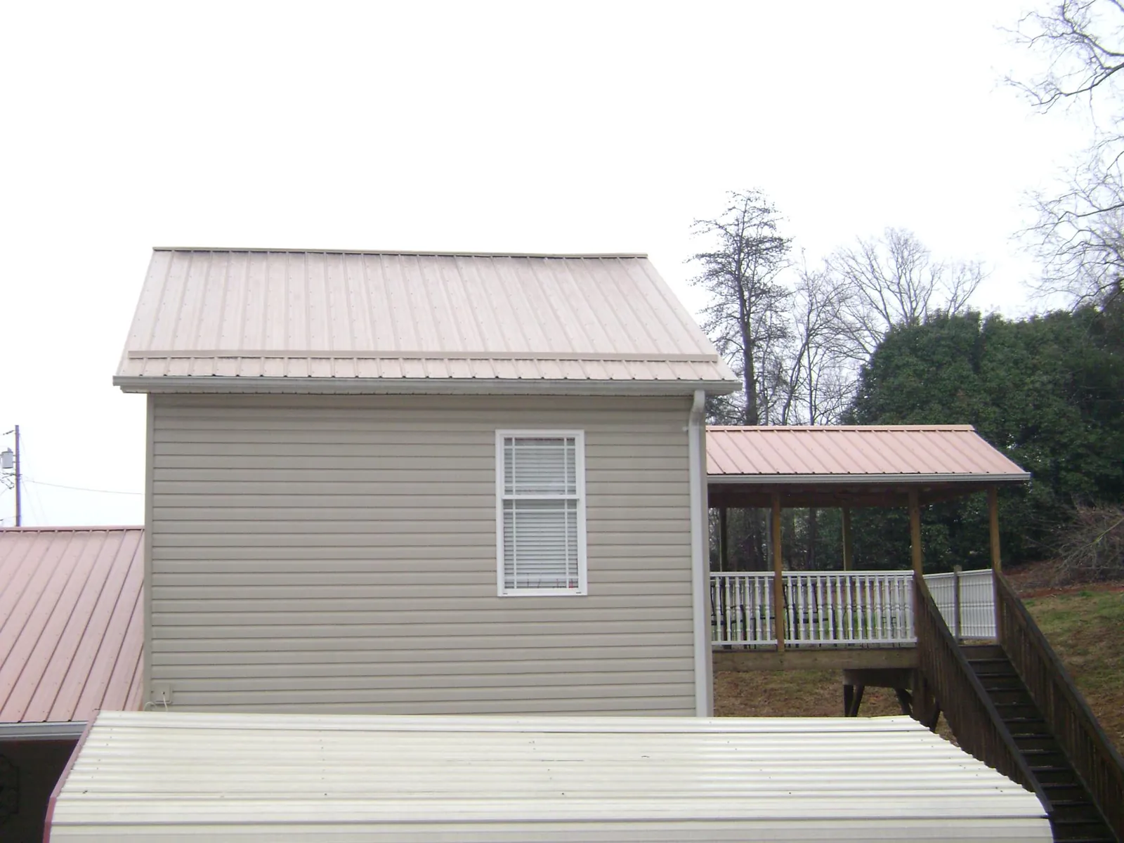 Tan metal roofs on a two story addition and attached porch, from a Roof Replacement job in Daisytown