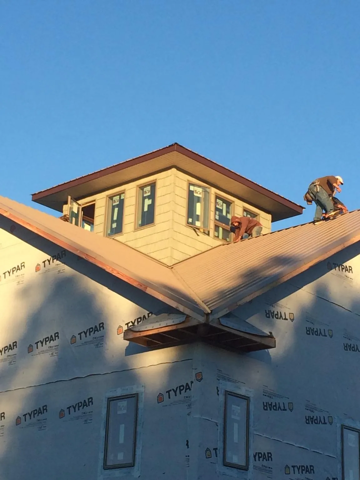 Roofers working around a rooftop cupola on a new metal roof at sunset — Roof Waterproofing in Daisytown by Roofing Brothers